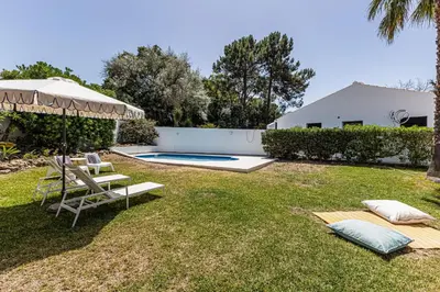 a backyard with a swimming pool and an umbrella at Villa Falésia in Olhos de Água