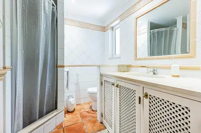 a bathroom with a sink and a toilet and a mirror at Villa Falésia in Olhos de Água