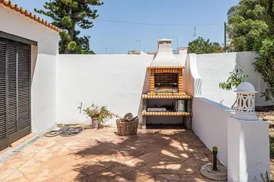 a patio with a grill next to a white wall at Villa Falésia in Olhos de Água