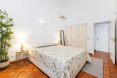 a white bedroom with a bed and a plant at Villa Falésia in Olhos de Água