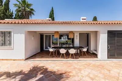 a house with a patio with a table and chairs at Villa Falésia in Olhos de Água