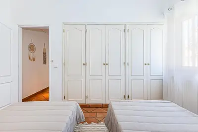 a bedroom with two beds and white cabinets at Villa Falésia in Olhos de Água