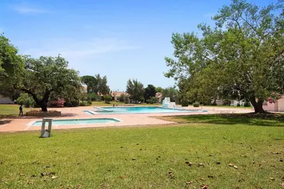 a swimming pool in a park with trees and grass at The Oura Stay in Albufeira
