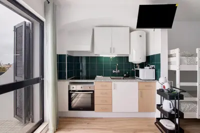 a kitchen with white cabinets and green tiles at The Oura Stay in Albufeira