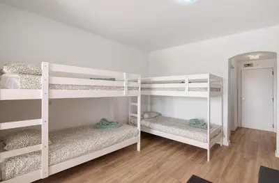 two white bunk beds in a room with wooden floors at The Oura Stay in Albufeira