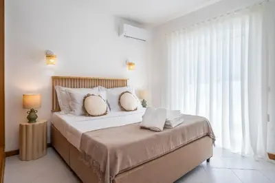 a white bedroom with a large bed with pillows at Alma Invicta Albufeira in Albufeira