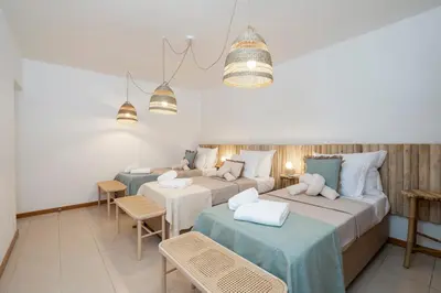 two beds in a room with two tables and chairs at Alma Invicta Albufeira in Albufeira