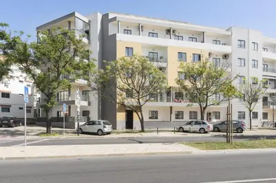 a large white building with cars parked in front of it at Modern 2BR Quarteira Apartment in Quarteira