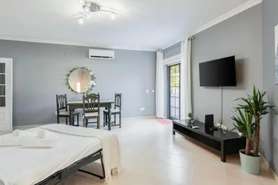 a bedroom with a bed and a dining room at Modern 2BR Quarteira Apartment in Quarteira