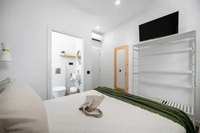 a white bedroom with a bed with a towel on it at Urban Bliss Boutique Guesthouse in Faro