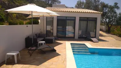 a house with a pool and an umbrella next to it at B&B Casa Encantada in Boliqueime