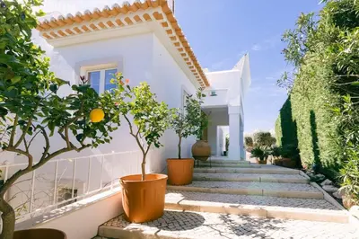 a white house with potted trees and stairs at Traumhaft schöne Villa mit Pool und Meerblick in Albufeira