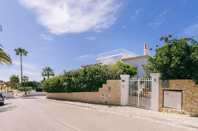 a white house with a fence and palm trees at Traumhaft schöne Villa mit Pool und Meerblick in Albufeira