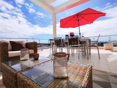 a patio with a table and a red umbrella at Sol Mar Penthouse by Da Costa in Albufeira