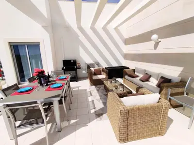 a living room with a couch and a table and chairs at Sol Mar Penthouse by Da Costa in Albufeira