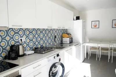 a kitchen with white cabinets and blue and white wallpaper at Casas Sao Luis in Faro