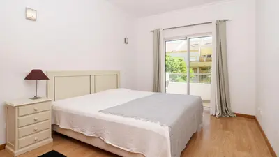 a bedroom with a white bed and a wooden closet at Falesia Marina in Quarteira