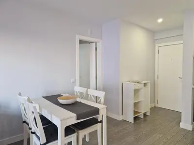 a white dining room with a table and chairs at Quarteira flat AC balcony and view in Quarteira