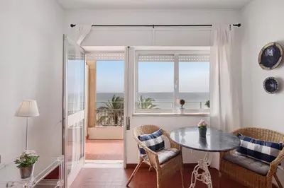 a living room with a table and a view of the ocean at Apartamento Mar Azul - Quarteira in Quarteira