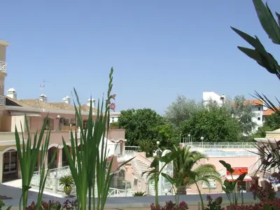 a view of a building with plants in the foreground at Vila Lusa Marina in Vilamoura