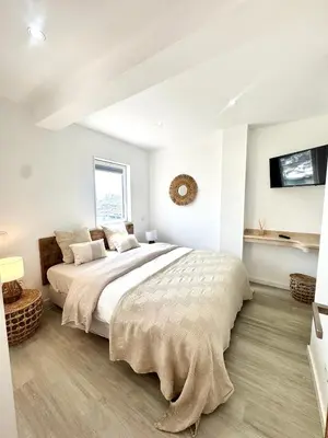 a white bedroom with a large bed and a tv at FM Marina Vilamoura in Quarteira