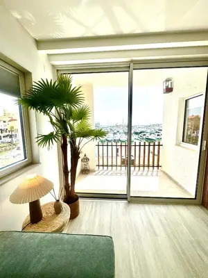 a living room with a green couch and a palm tree at FM Marina Vilamoura in Quarteira