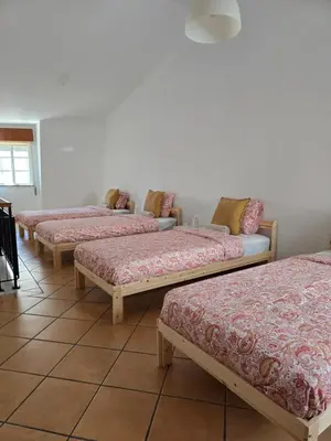 four beds lined up in a row in a room at Casa Alfazema in Faro