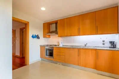 a kitchen with wooden cabinets and a sink at Penthouse with Pool View in Albufeira by Lovelystay in Albufeira