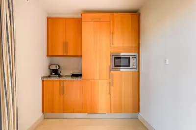 a kitchen with wooden cabinets and a microwave at Penthouse with Pool View in Albufeira by Lovelystay in Albufeira