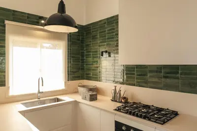 a kitchen with green tiles on the wall and a sink at Aldeamento Aldeia do Golf V3 in Vilamoura