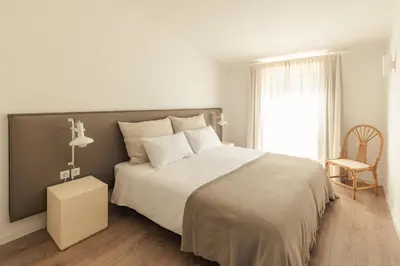 a bedroom with a bed and a chair and a window at Aldeamento Aldeia do Golf V3 in Vilamoura