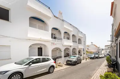 a white building with two cars parked on the street at Modern 1BDR with Sea View in Albufeira by LovelyStay in Albufeira