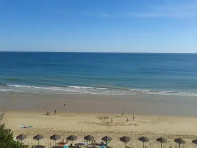 a group of people on a beach with umbrellas at 2 bedroom Apartment Falésia Beach in Albufeira