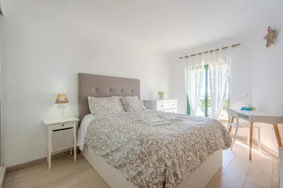 a white bedroom with a bed and a desk at Salgados Sunset and Sea View Apartment in Guia