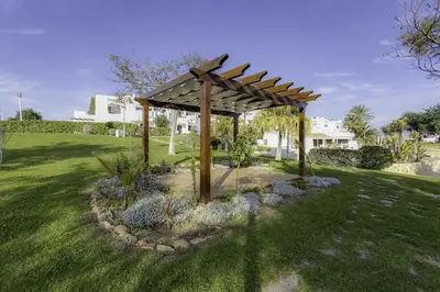a garden with a wooden pergola in a yard at CLUB ALBUFEIRA - 2 bedroom apartment, air conditioning and pools in Albufeira