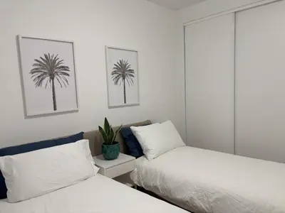 a bedroom with two beds and a palm tree on the wall at Casa Verde in Albufeira