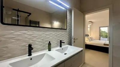 a bathroom with a sink and a mirror and a bed at Amêndoa by Check-in Portugal in Quarteira