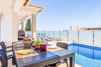 a patio with blue chairs and a swimming pool at Villa Sunflower in Albufeira