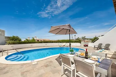 a swimming pool with a table and an umbrella at Villa Barbara in Albufeira