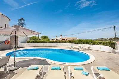 a swimming pool with chairs and an umbrella at Villa Barbara in Albufeira