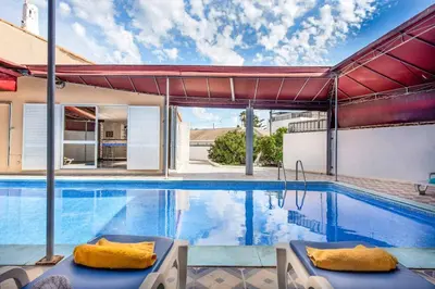 a swimming pool with two chairs next to a house at Villa Mogan in Albufeira