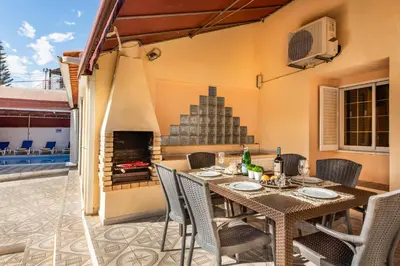 a patio with a table and chairs and a fireplace at Villa Mogan in Albufeira