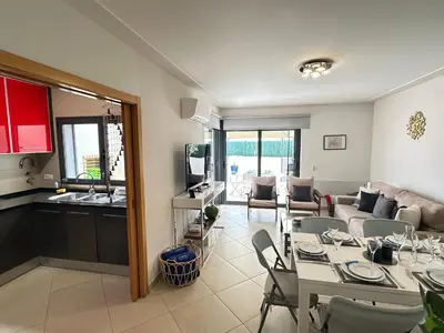 a kitchen and a living room with a table and chairs at Monte da Vinha By FHR in Quarteira