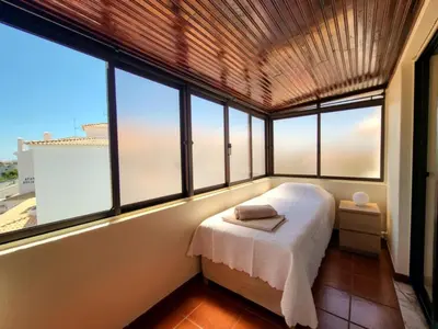 a bedroom with a bed in a room with windows at Sun House in Albufeira