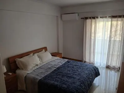 a bedroom with a bed with a blue blanket and a window at Albufeira Baixa Apartment in Albufeira