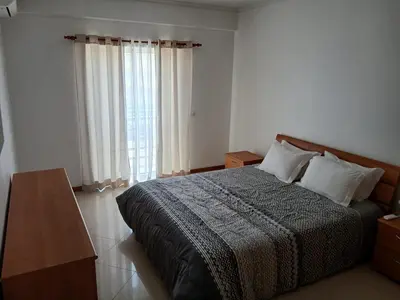 a bedroom with a bed and a large window at Albufeira Baixa Apartment in Albufeira