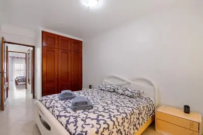 a bedroom with a bed with a white and black comforter at Excellent Apartment in Olhos D´Água in Olhos de Água
