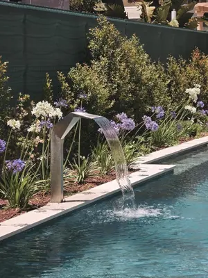 a water fountain in a swimming pool with flowers at Villa São Rafael in Albufeira