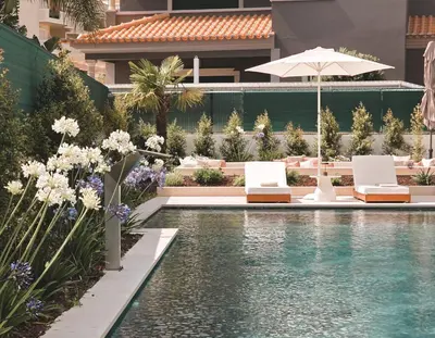 a swimming pool with two chairs and an umbrella at Villa São Rafael in Albufeira
