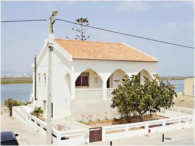 a white church with a white fence and a building at Lazaro Beach House in Faro